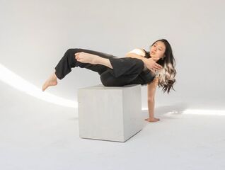 Dancer with long hair, on white box with white background, wearing black outfit
